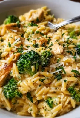 Cheesy chicken broccoli orzo dish served in a bowl, garnished with herbs.