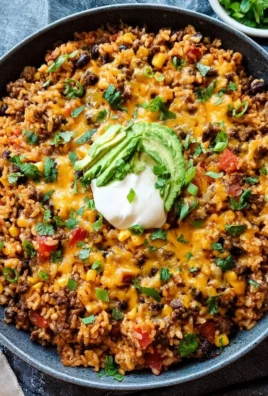 Delicious cheesy taco rice skillet served in a pan with toppings.