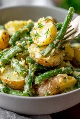 Creamy green bean potato salad served in a bowl with fresh herbs