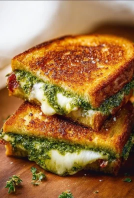 Pesto grilled cheese sandwich with melted cheese and fresh basil pesto