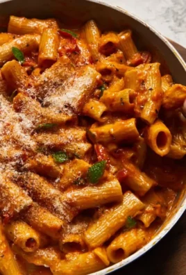Creamy roasted red pepper pasta served in a bowl with fresh herbs.