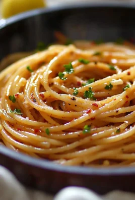 A bowl of spicy spaghetti pasta topped with herbs and chili flakes