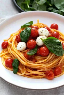 A delicious plate of tomato pasta garnished with fresh basil and parmesan cheese