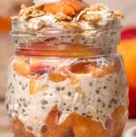 Bowl of creamy peach overnight oats topped with fresh peach slices