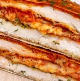 High Protein Chicken Parm Crunchwrap on a wooden plate with fresh herbs