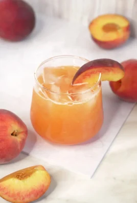 Glass of refreshing peach lemonade with slices of peach and lemon