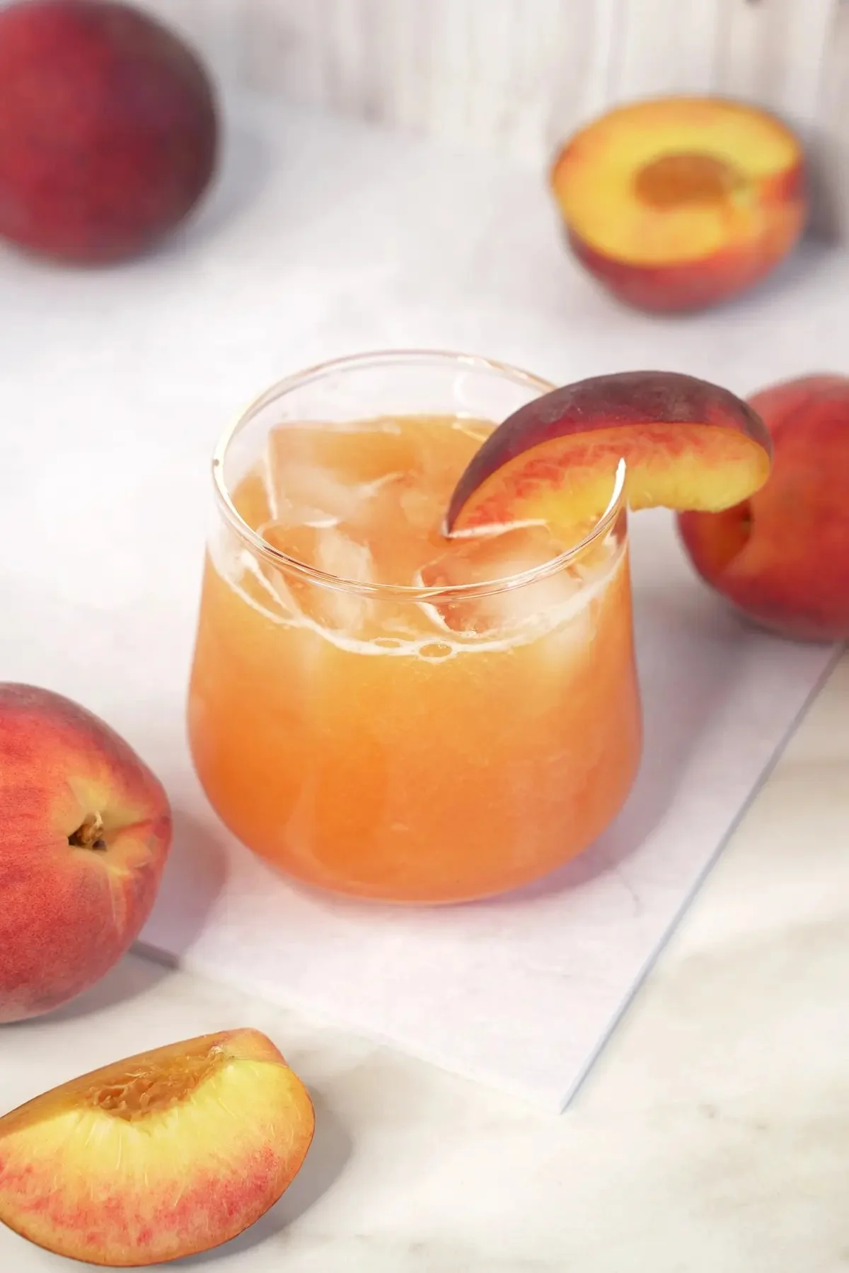 Glass of refreshing peach lemonade with slices of peach and lemon