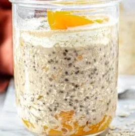 Bowl of peach overnight oats topped with fresh peach slices and nuts