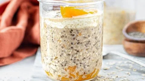 Bowl of peach overnight oats topped with fresh peach slices and nuts