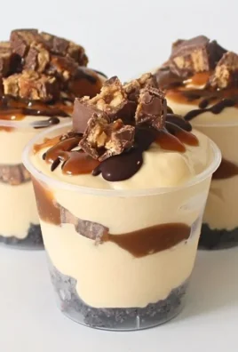 Delicious homemade Snickers Dessert Cups topped with caramel and peanuts.