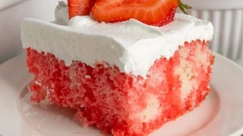 Delicious strawberry poke cake topped with whipped cream and fresh strawberries.