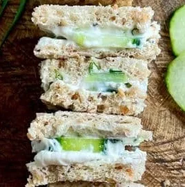 Vegan cucumber sandwiches on a platter with fresh herbs and spices