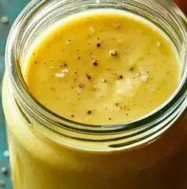 Bowl of anti-inflammation garlic-lemon vinaigrette drizzled over fresh salad.