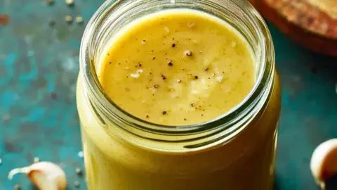 Bowl of anti-inflammation garlic-lemon vinaigrette drizzled over fresh salad.