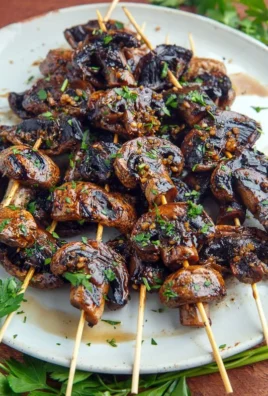 Balsamic garlic grilled mushroom skewers on a platter, garnished and ready to eat.