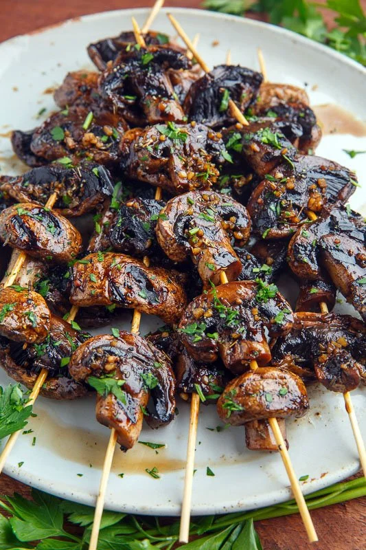 Balsamic garlic grilled mushroom skewers on a platter, garnished and ready to eat.