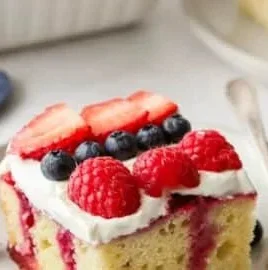 Delicious Berry Poke Cake topped with fresh berries and whipped cream