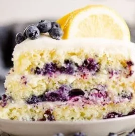 A delicious blueberry lemon layer cake decorated with fresh blueberries and lemon slices.
