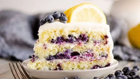 A delicious blueberry lemon layer cake decorated with fresh blueberries and lemon slices.