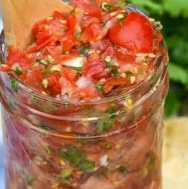 Fresh cherry tomato salsa in a bowl garnished with herbs.
