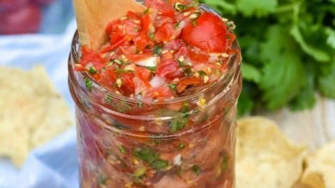 Fresh cherry tomato salsa in a bowl garnished with herbs.