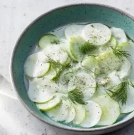 Creamy cucumber salad with fresh herbs and dressing served in a bowl