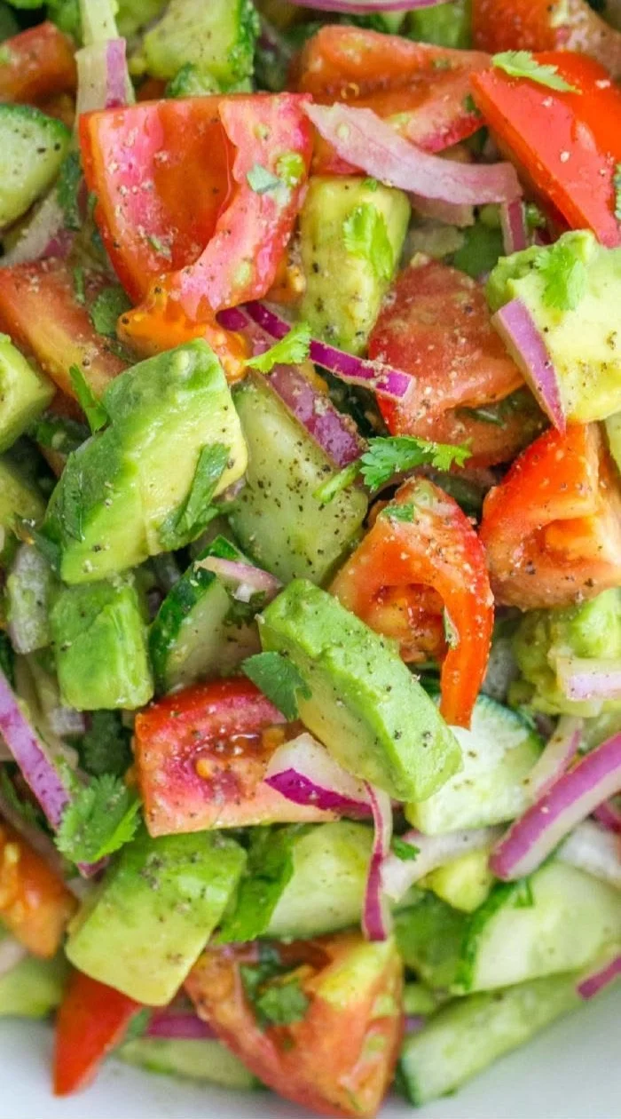 Cucumber Tomato Avocado Salad garnished with herbs in a bowl
