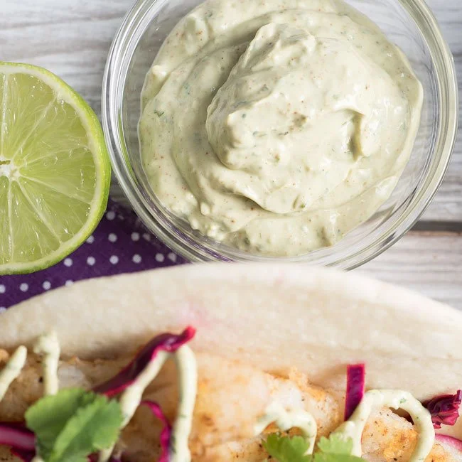 Homemade fish taco sauce drizzled over fresh fish tacos
