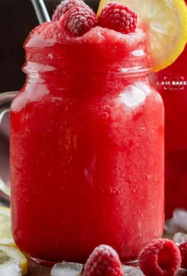 Delicious frozen raspberry lemonade in a glass, garnished with raspberries.
