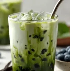 Iced Blueberry Vanilla Matcha Latte topped with blueberries and matcha powder