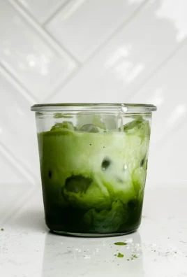 A refreshing Iced Matcha Latte topped with frothy milk and vibrant green matcha powder