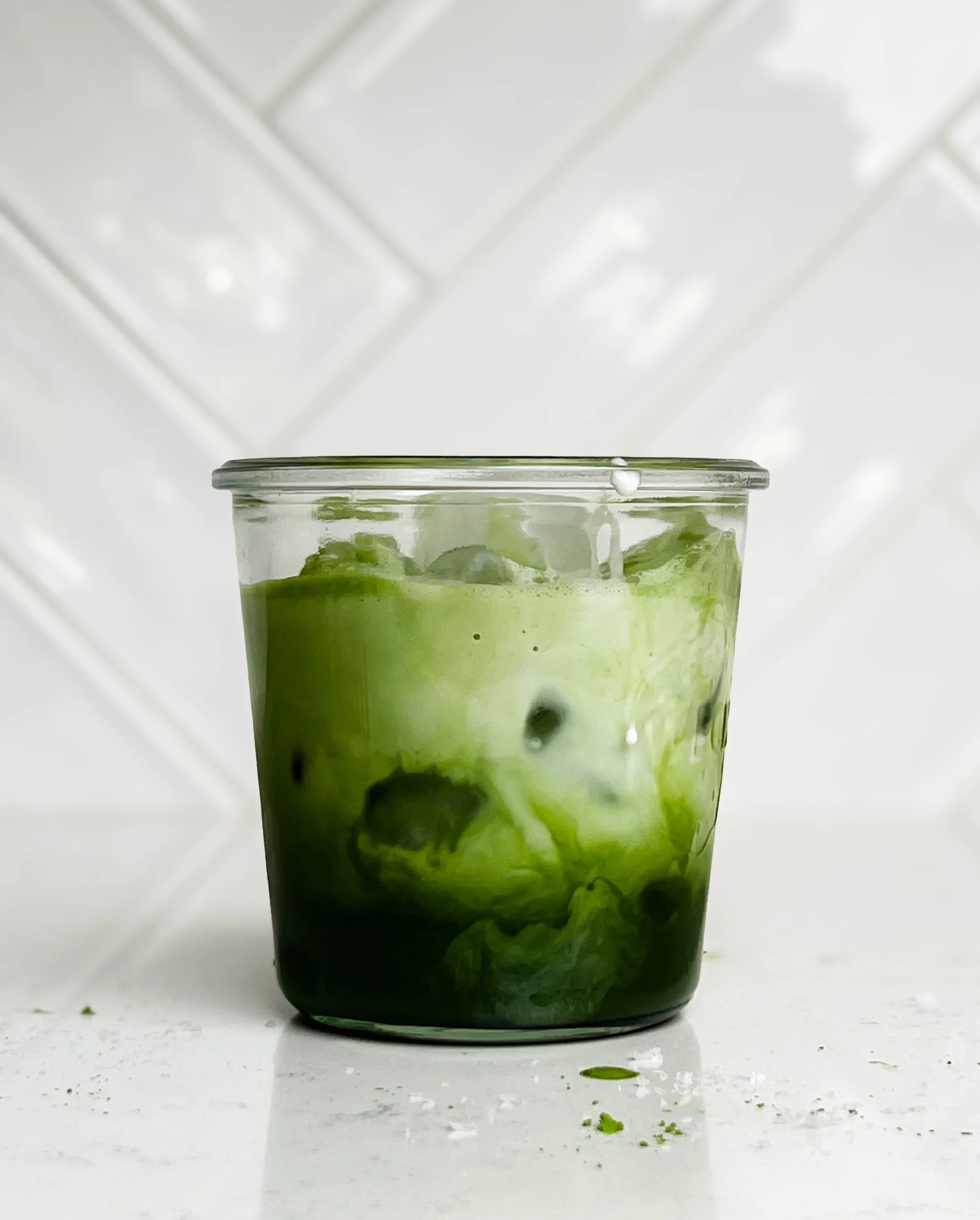 A refreshing Iced Matcha Latte topped with frothy milk and vibrant green matcha powder