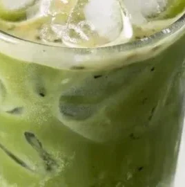 Iced Vanilla Matcha Latte in a glass with whipped cream and a straw