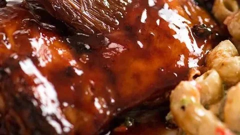 Delicious sticky grilled chicken garnished with herbs on a plate.
