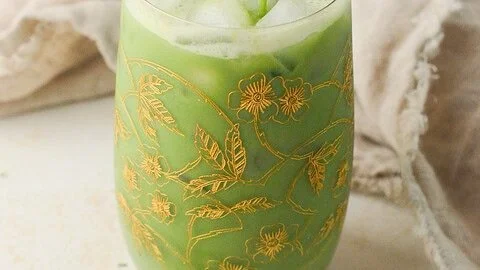Refreshing iced matcha latte topped with milk and ice in a glass