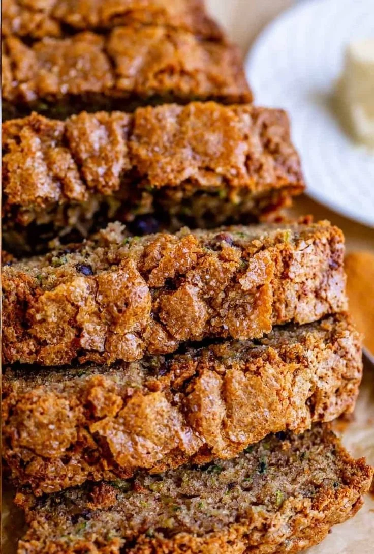Sliced homemade zucchini bread with nuts and spices on a wooden board